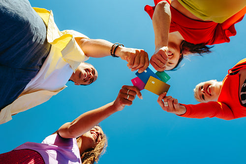 Young adults hold colorful credit cards for youth finance outdoors