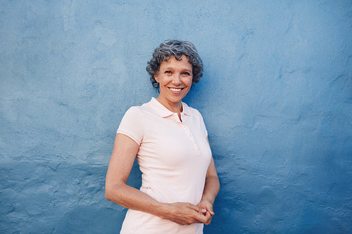 Smiling mature woman standing against blue background