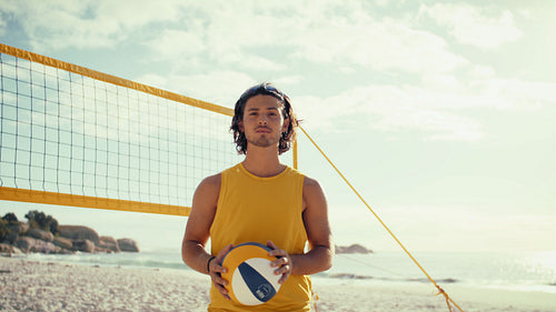 Happy male beach volleyball player tossing ball into the air
