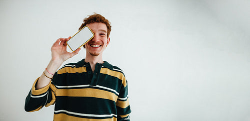 Young man portrait with smartphone in studio for mobile technology and social media concept