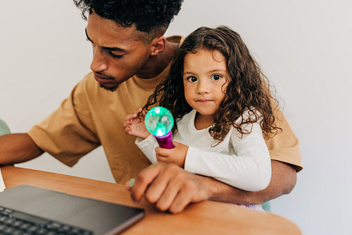 Cute little girl sitting with her dad in his home office