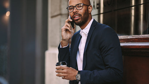 Man in business suit talking over cell phone outdoors