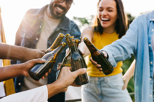 Group of friends cheering with beers during an outdoor summer celebration