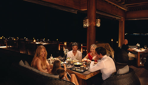 Family enjoying dinner at a cozy outdoor restaurant at night