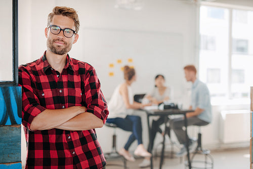 Relaxed business man in office with colleagues in background