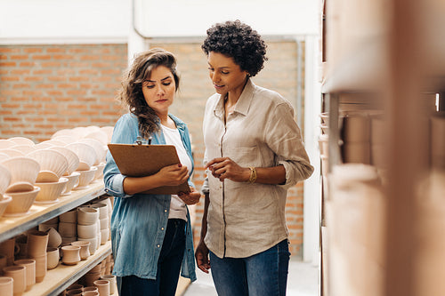 Two young businesswomen working together in their ceramic store