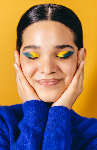 Loving her makeup look, woman embraces her face in a studio