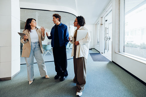Three professionals talk in office lobby