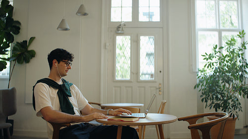 Speaking man joins a laptop video call in a cafe workspace