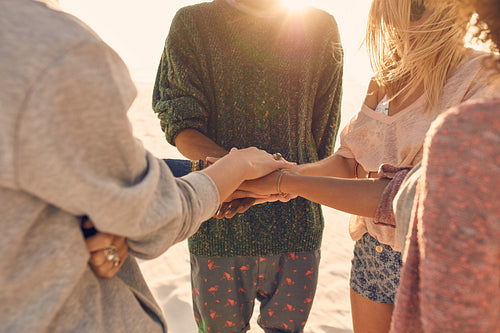 Group of friends with hands on stack at seaside