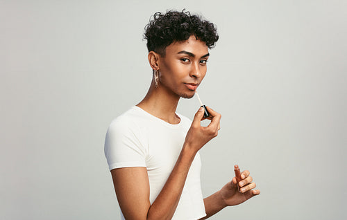 Gay man applying lip gloss