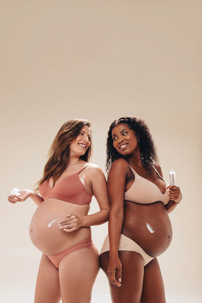 Pregnant women smiling and applying self care belly cream for prenatal wellness