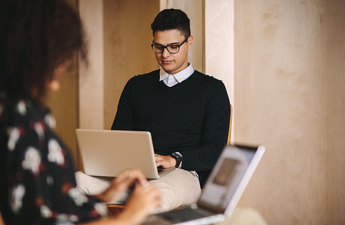 Business people working on laptop computers sitting on chairs