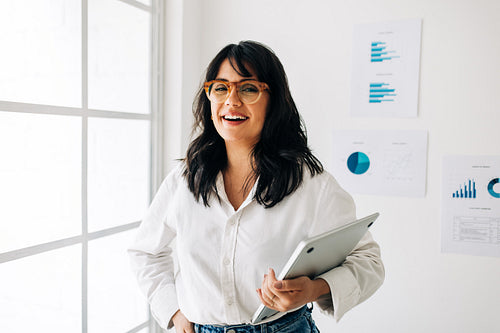 Data analyst standing in an office and looking at the camera