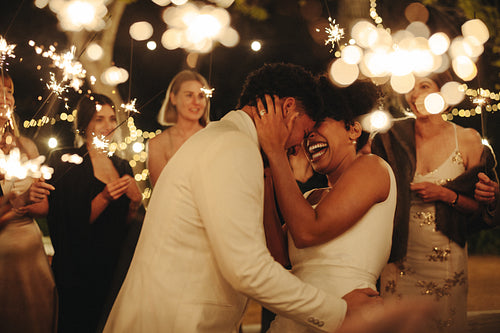 Joyful couple celebrating their wedding surrounded by sparklers and friends