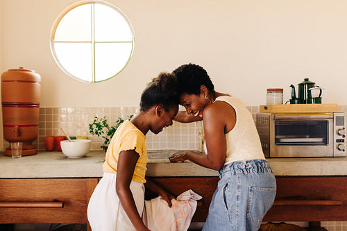 Black mother and daughter bonding in a Brazilian kitchen