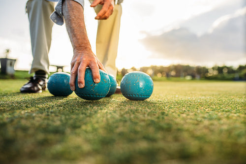 Close up of a man picking a boules standing in a lawn