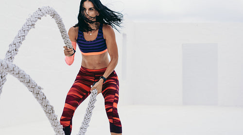 Fitness woman doing workout using battle ropes