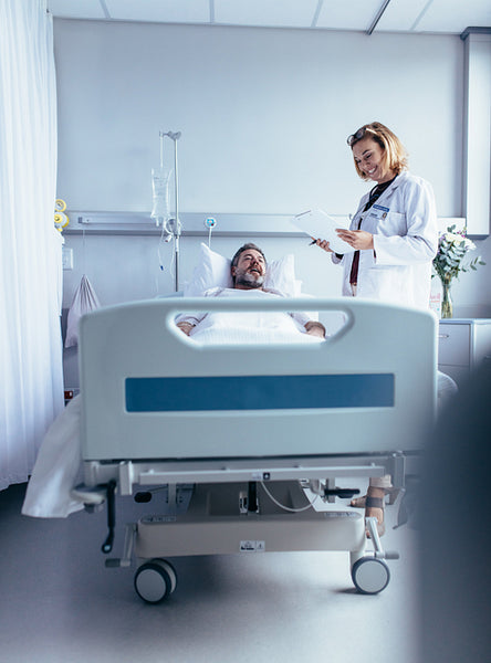 Doctor with clipboard visiting man at hospital ward