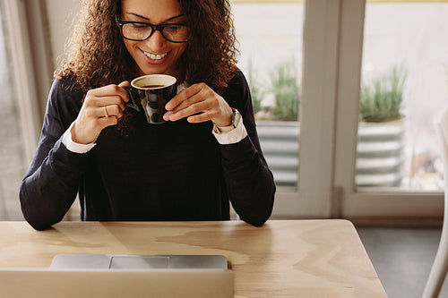 Happy young woman at cafe with laptop