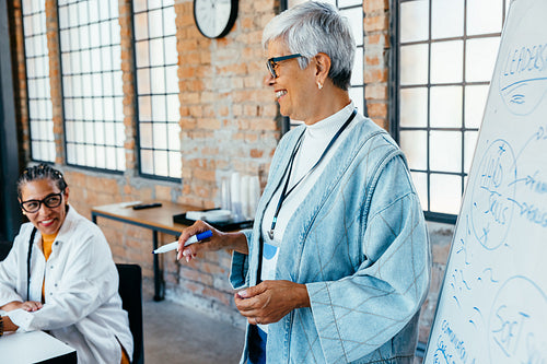 Cheerful senior businesswoman leading a successful meeting with enthusiasm and confidence in a contemporary workspace