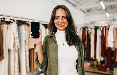 Small business owner holding up a smartphone, recommending using mobile apps