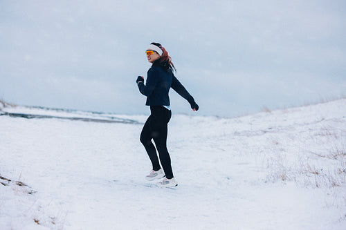 Outdoor training keeps the running woman moving through winter snow alone