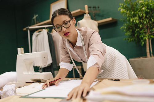 Dressmaker designing clothes pattern on paper