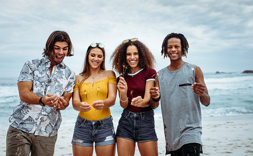 Happy friends partying on the beach with sparklers
