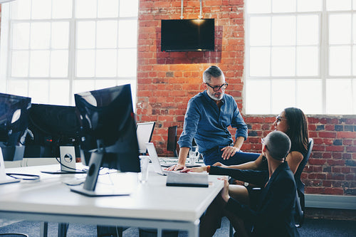 Three businesspeople having a discussion while working together