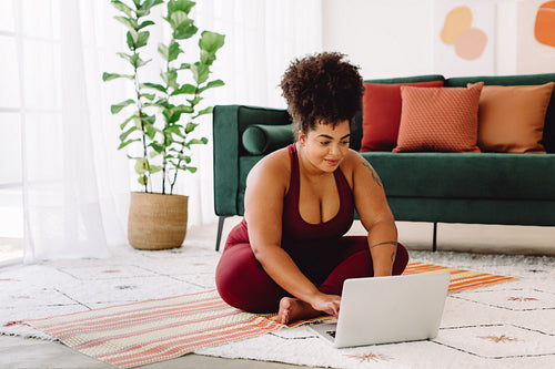 Plus size woman using laptop while exercising at home