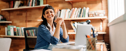 Confident young businesswoman smiling in her home office