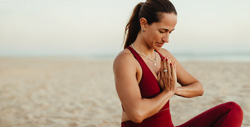 Woman practicing yoga meditation on a peaceful beach at sunrise