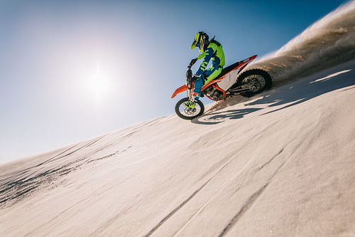 Motocross biker riding on sand dune