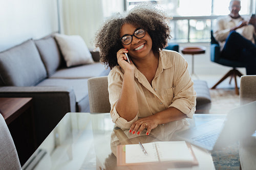 Happy mature businesswoman talking on phone during meetings at home