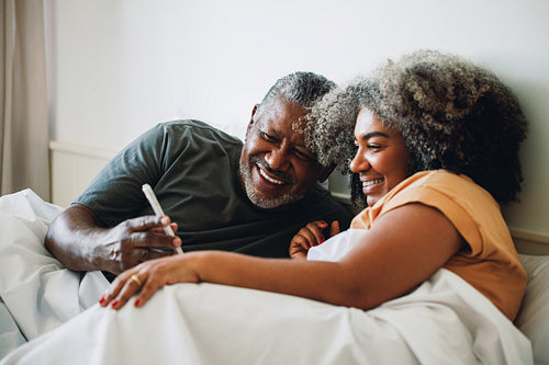 Mature couple enjoying a morning together in bed, sharing a moment with technology