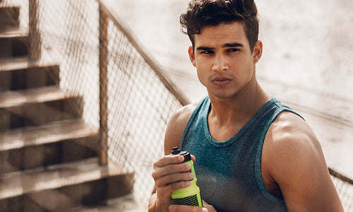 Healthy athletic man holding bottle of water