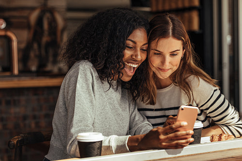 Friends sitting in a cafe looking at mobile phone