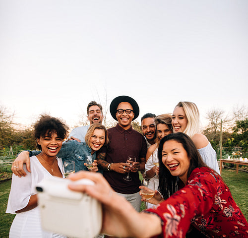 Group of friends taking picture with instant camera