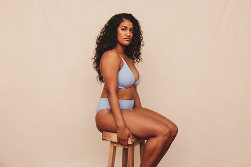 Body positive young woman sitting comfortably in a blue underwear