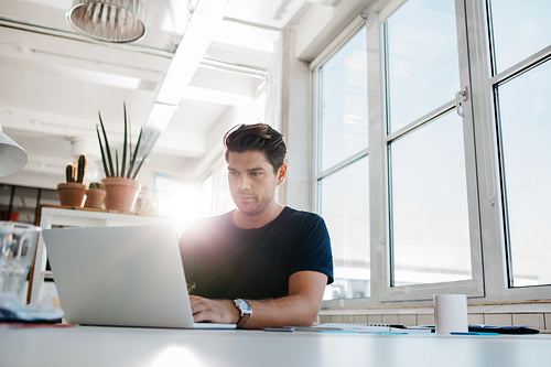 Young male executive working on laptop at his desk.