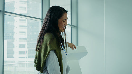 Professional woman speaking at a podium during a conference with city views