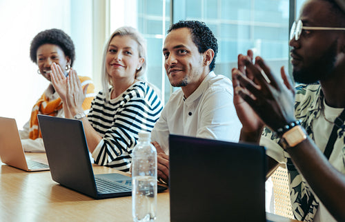 Diverse colleagues applauding in a business meeting in a modern office setting