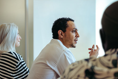 Multiracial businessman engaged in a thoughtful office discussion with colleagues