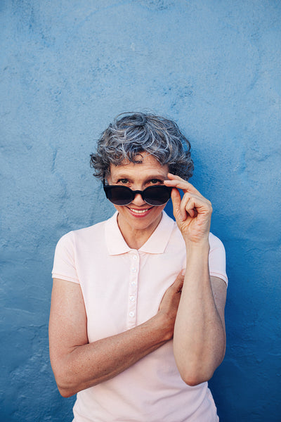 Attractive senior woman peeking over sunglasses