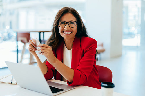Confident female professional working on a laptop in a casual office setting