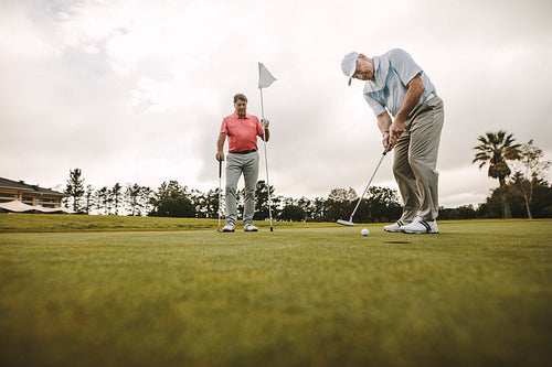 Senior men playing golf on the green