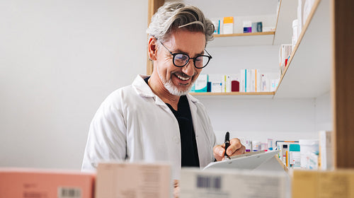 Male pharmacist filling prescriptions in a chemist