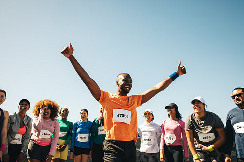 Runner celebrating victory with crowd at marathon finish line