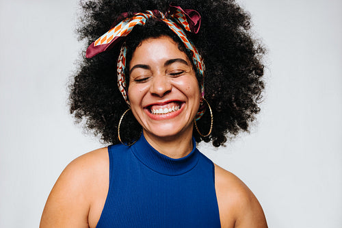 Woman with curly hair smiling happily with her eyes closed